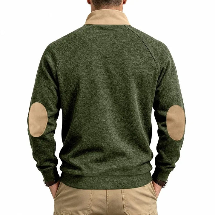 Man wearing a dark green marled half-zip top with a tan collar and tan elbow patches, seen from the back.