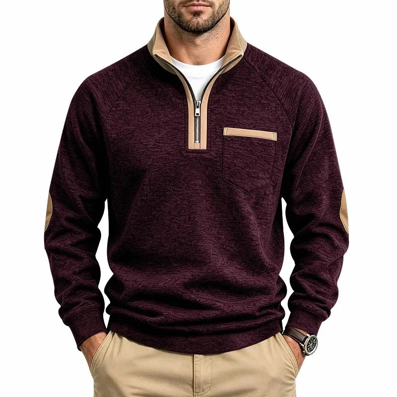 Man wearing a textured burgundy knit sweatshirt with a tan quarter-zip collar, matching chest pocket trim, and elbow patches.