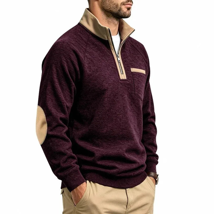 Man wearing a marled maroon knit sweatshirt with a tan quarter-zip collar, elbow patches, and a small chest pocket.