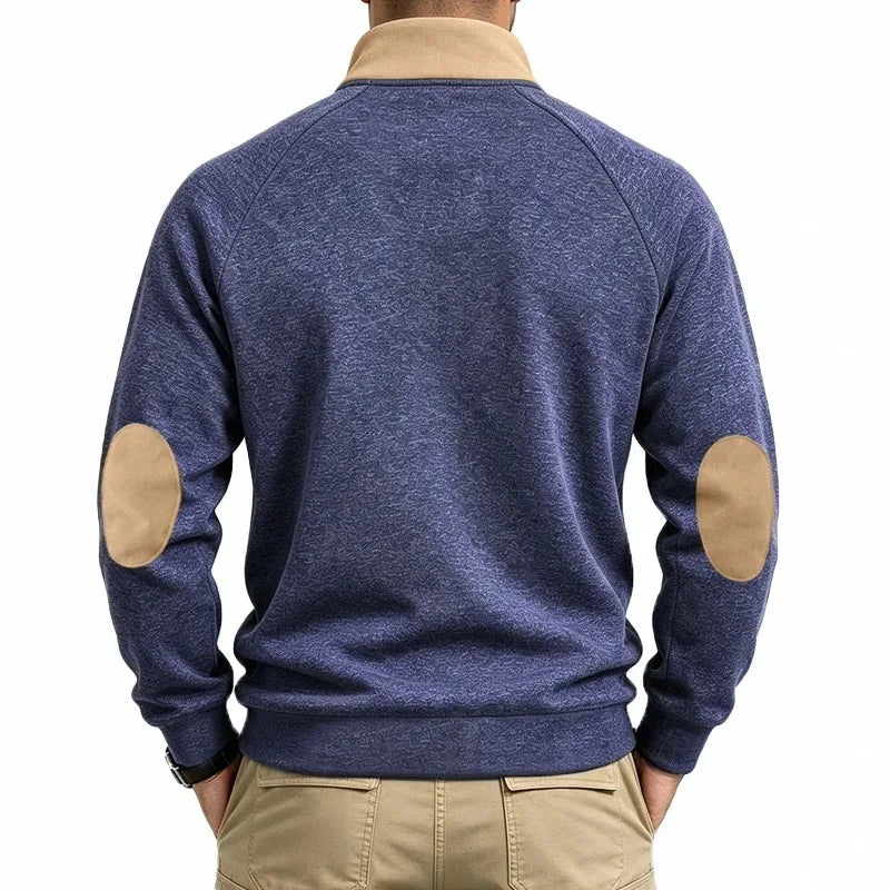 Man wearing a blue marled knit sweatshirt with tan collar and oval elbow patches, viewed from the back.