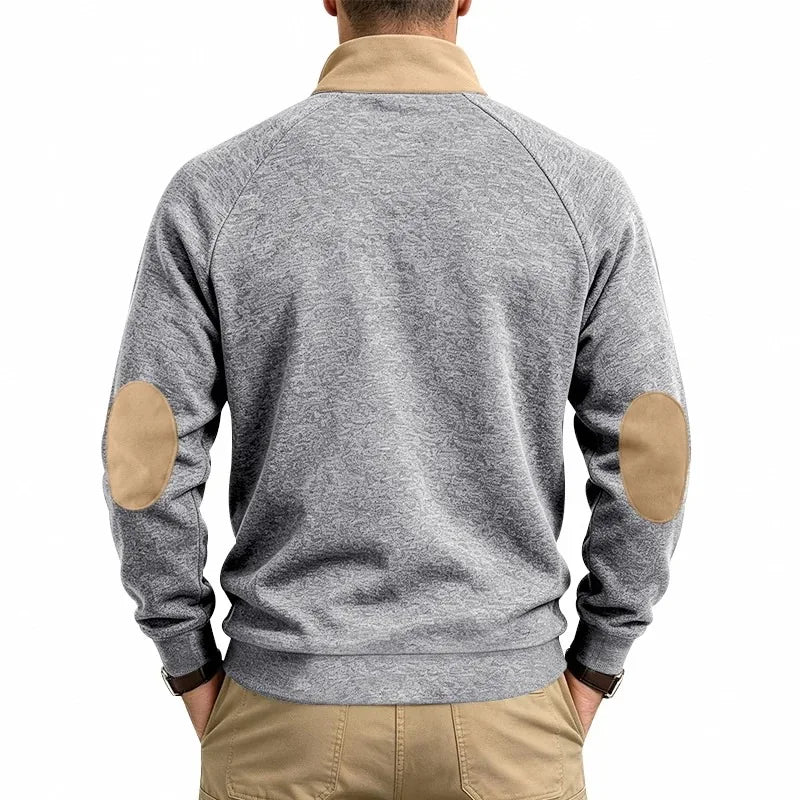 Man wearing a gray patterned knit sweatshirt with tan elbow patches and a tan quarter-zip collar, viewed from the back.