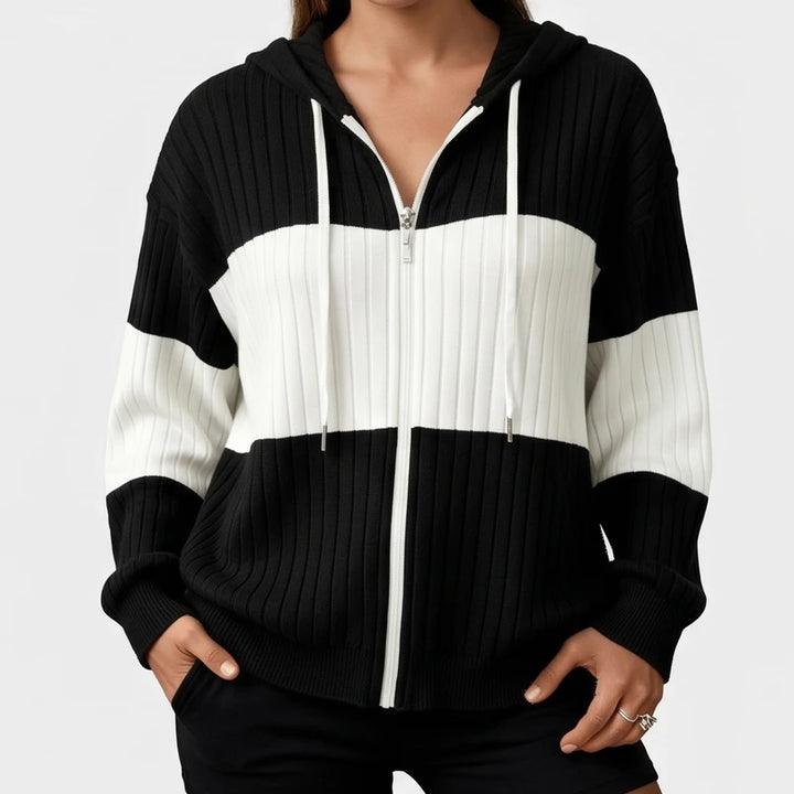 Woman wearing a black and white ribbed knit zip-up hoodie with a white horizontal stripe across the chest.