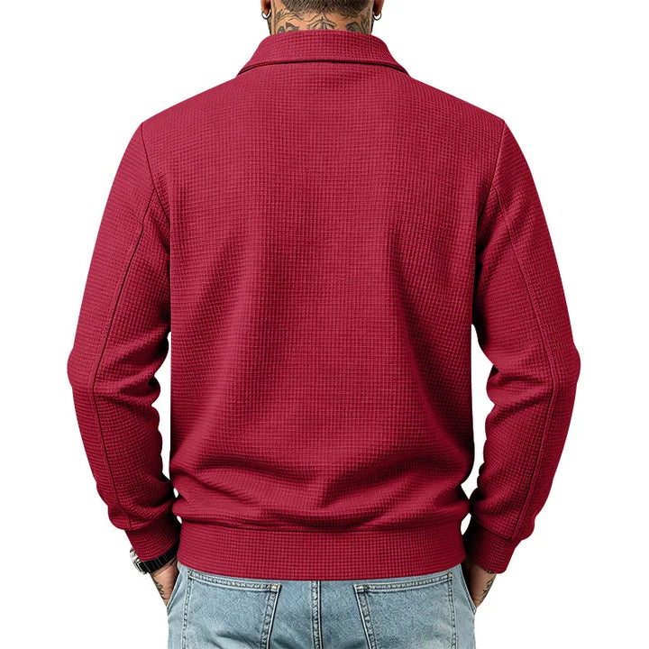 Man wearing a textured deep red collared jacket with ribbed cuffs and hem, over light wash jeans, seen from the back.