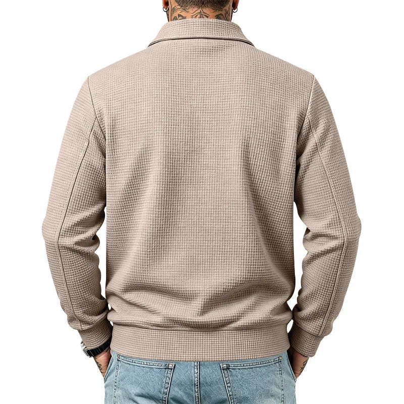 Man wearing a beige waffle-knit jacket with a collar and ribbed cuffs, paired with light wash blue jeans, back view.