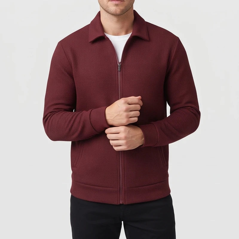 Man wearing a dark red waffle-knit zip-up jacket with a collar and pockets, adjusting his cuff.