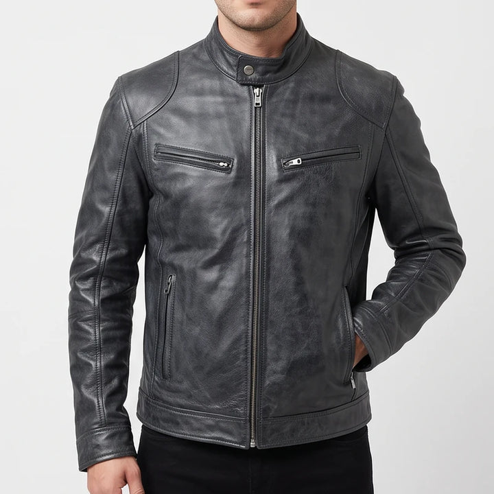 Man wearing a distressed charcoal leather biker jacket with a band collar and zippered pockets against a plain white backdrop.
