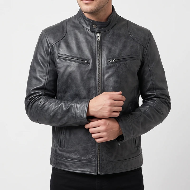 Man wearing a dark grey leather biker jacket with a mandarin collar and zippered chest pockets against a plain background.