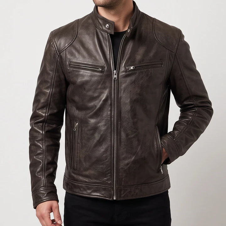 Man wearing a fitted dark brown leather jacket with multiple zippered pockets and a snap collar against a white background.