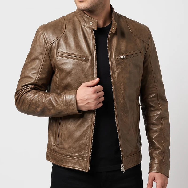 Man wearing a brown leather biker jacket with zippered chest pockets over a black shirt against a plain background.