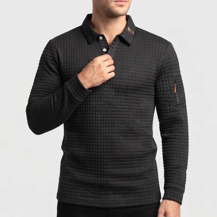 Man wearing a dark gray quilted long sleeve polo shirt with white buttons, an orange sleeve accent, and a textured pattern.