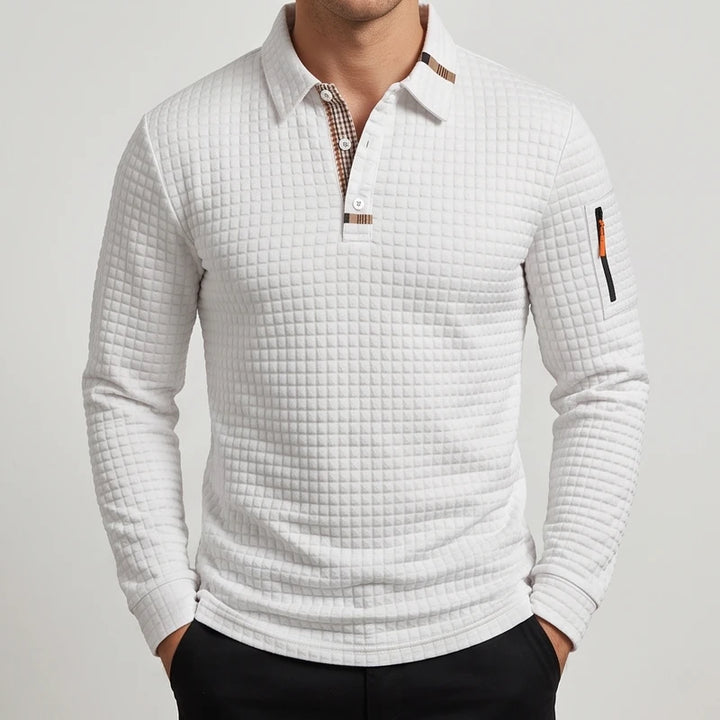 Man wearing a white quilted long sleeve polo shirt with a plaid collar lining and a small zippered sleeve pocket.