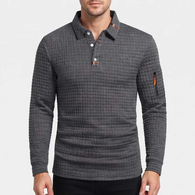 Man wearing a dark gray waffle-knit long-sleeve polo with a three-button placket, contrasting brown collar lining, and orange sleeve zipper.