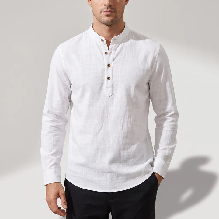 Man wearing a white, textured long-sleeve shirt with a band collar and three visible brown buttons.