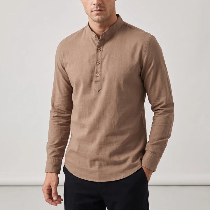 Man wearing a long sleeve collared shirt in tan brown with a four-button placket and rounded hem, hand in pocket.