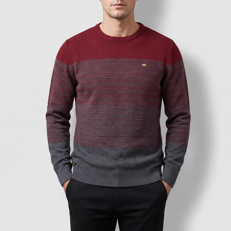 Man wearing a burgundy and gray color block sweater with horizontal striped texture and a small chest patch.