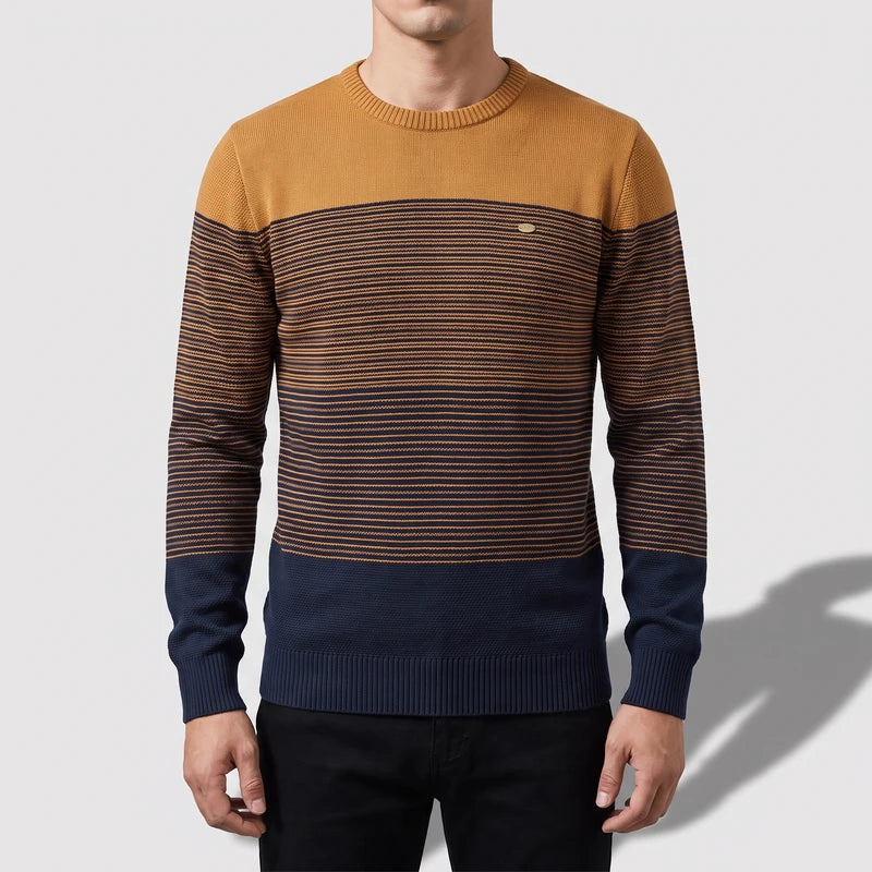 Man wearing a crew neck sweater with a mustard yellow top, fading into navy blue stripes, and a solid navy hem.
