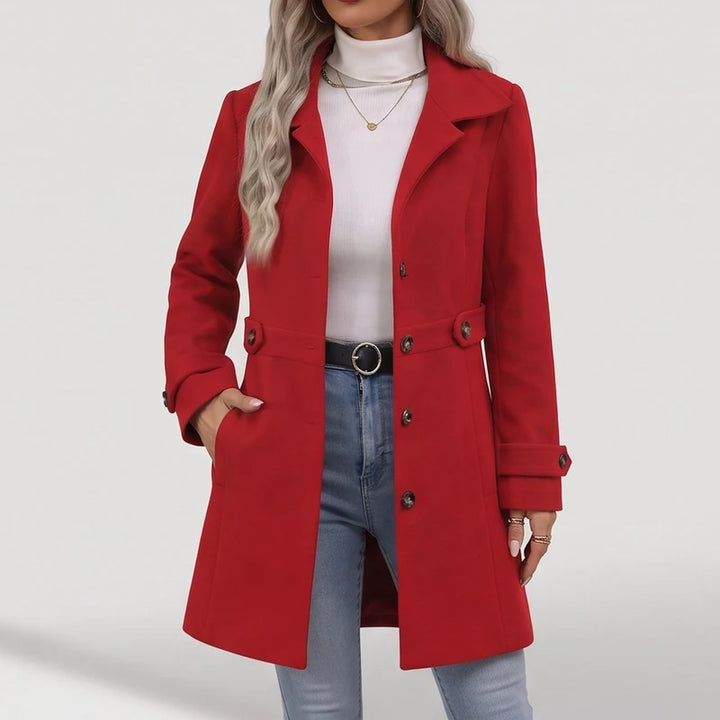 Woman wearing a bright red long wool coat with large lapels and buttoned details, one hand in a pocket.