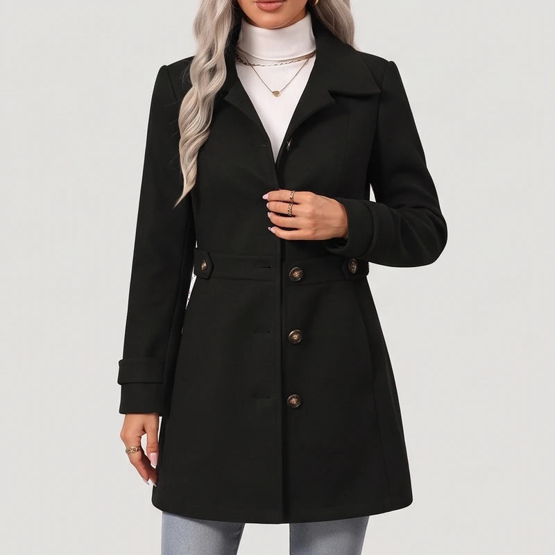 Woman wearing a black coat with large brown buttons, a classic collar, and decorative waist tabs over a white turtleneck.