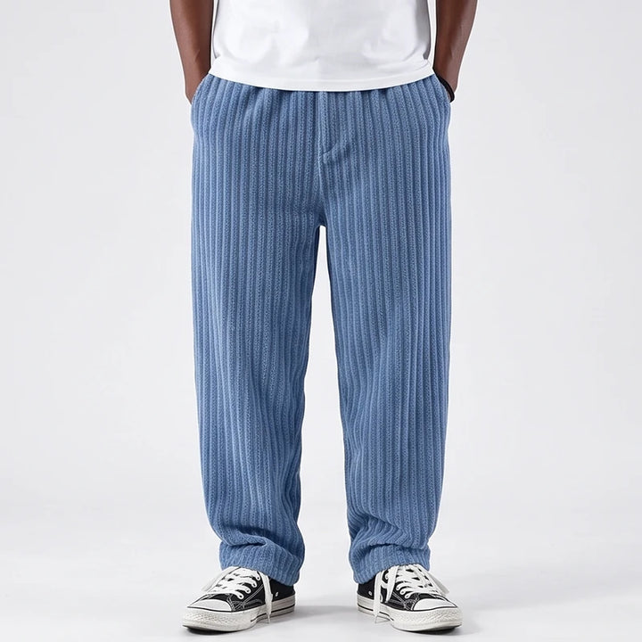Man wearing baggy light blue corduroy pants with an elastic waist and wide legs, hands in pockets.