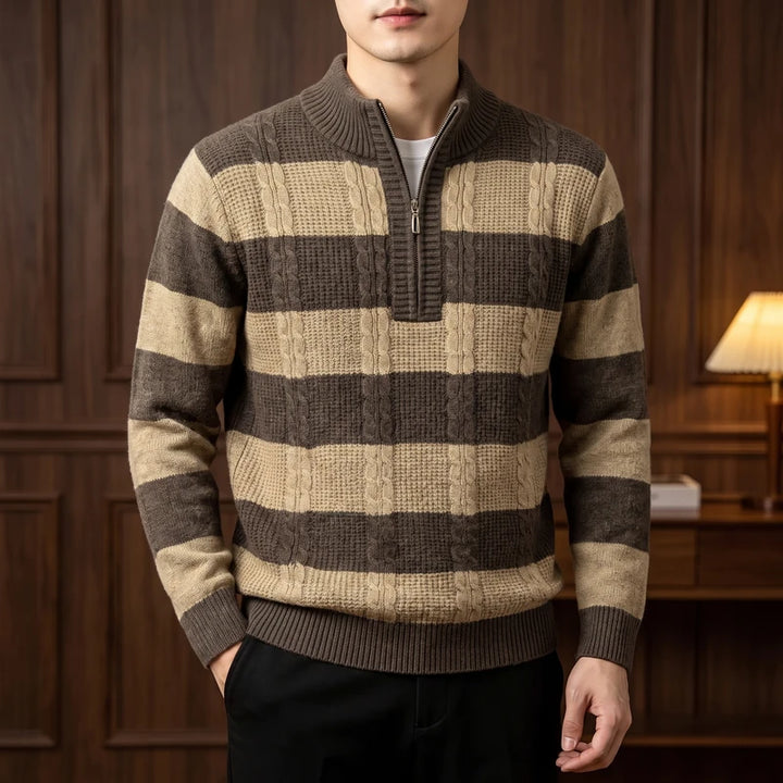 Man wearing a cable-knit half-zip sweater with dark brown and tan horizontal stripes over black pants.