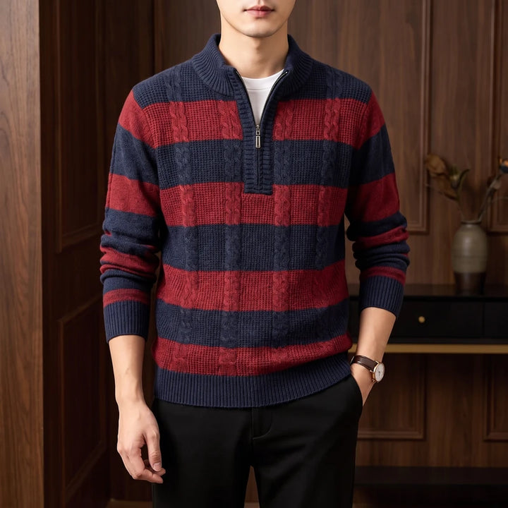 Man wearing a cable-knit half-zip sweater with horizontal navy and red stripes, paired with black pants.