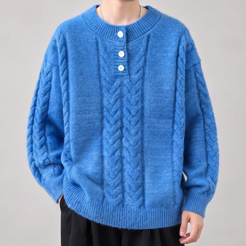 Man wearing a bright blue cable-knit sweater with white buttons on the placket, shown from the chest up.