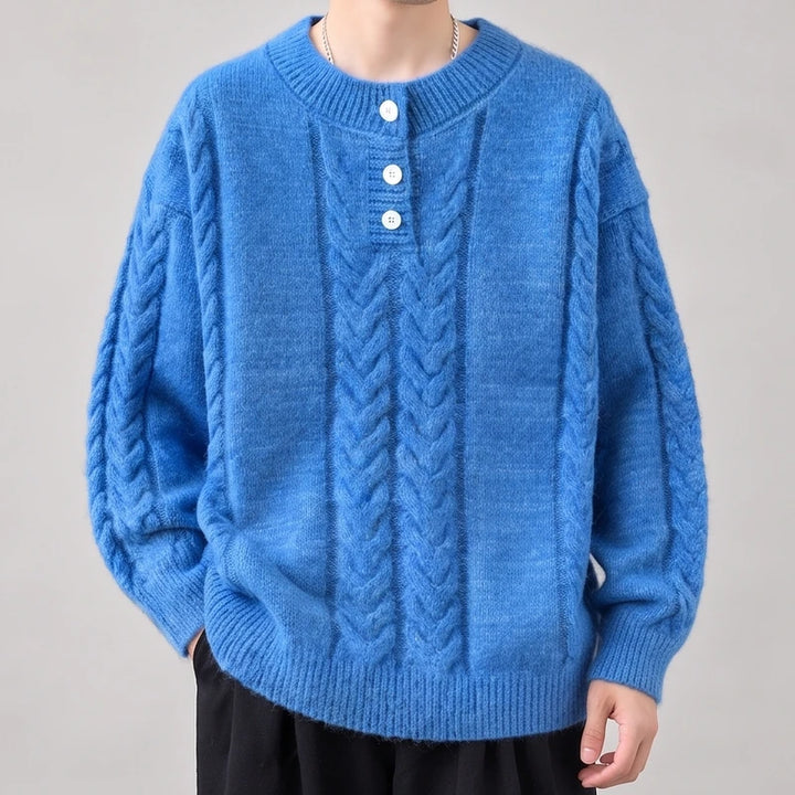 Man wearing a bright blue cable-knit sweater with white buttons on the placket, shown from the chest up.