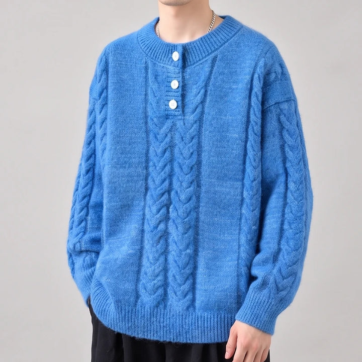 Man wearing a bright blue, fluffy cable-knit sweater with white buttons and a relaxed fit, standing against a neutral background.