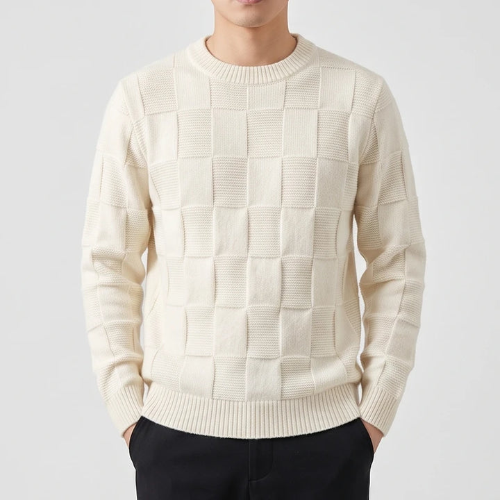Man wearing an off-white knitted crew neck sweater with a textured checkerboard pattern and ribbed trim.