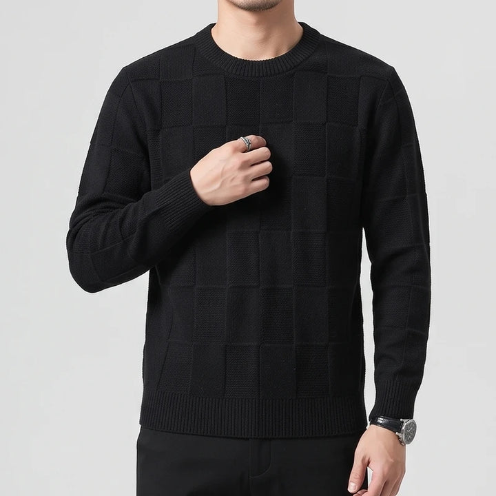 Man wearing a black checkered knit crew neck sweater with ribbed cuffs and hem, posing against a white background.