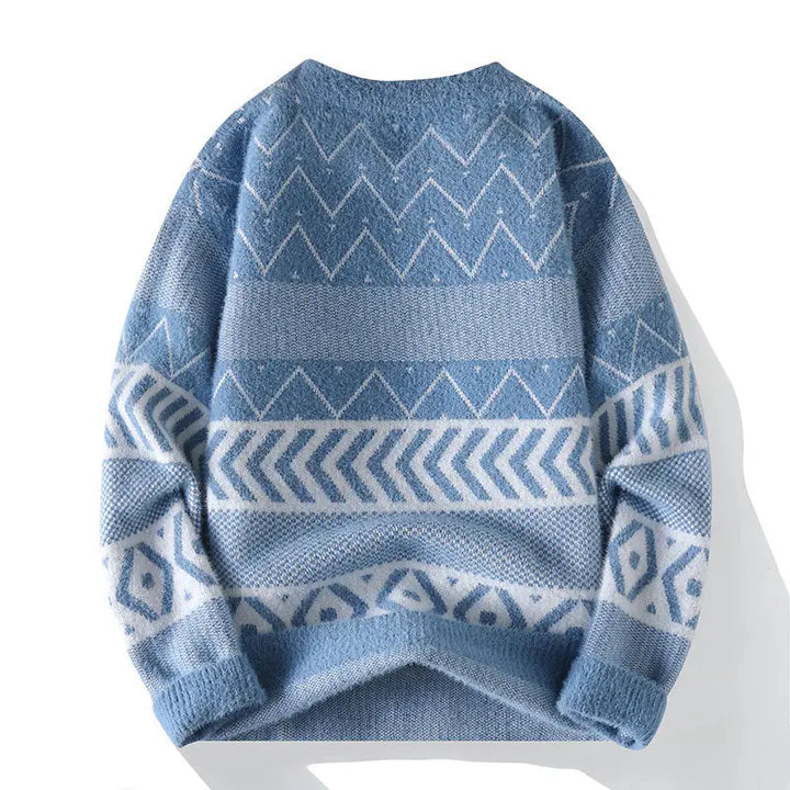 Flat lay of a light blue knit sweater with white geometric patterns, including zigzags and chevron stripes.