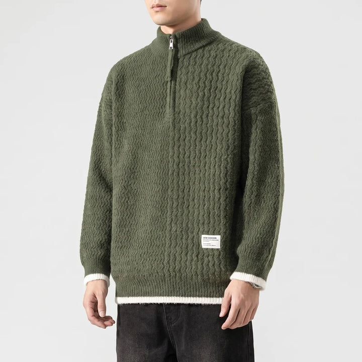 Man wearing a textured dark green half-zip sweater with a white stripe at the hem and cuffs, against a white background.