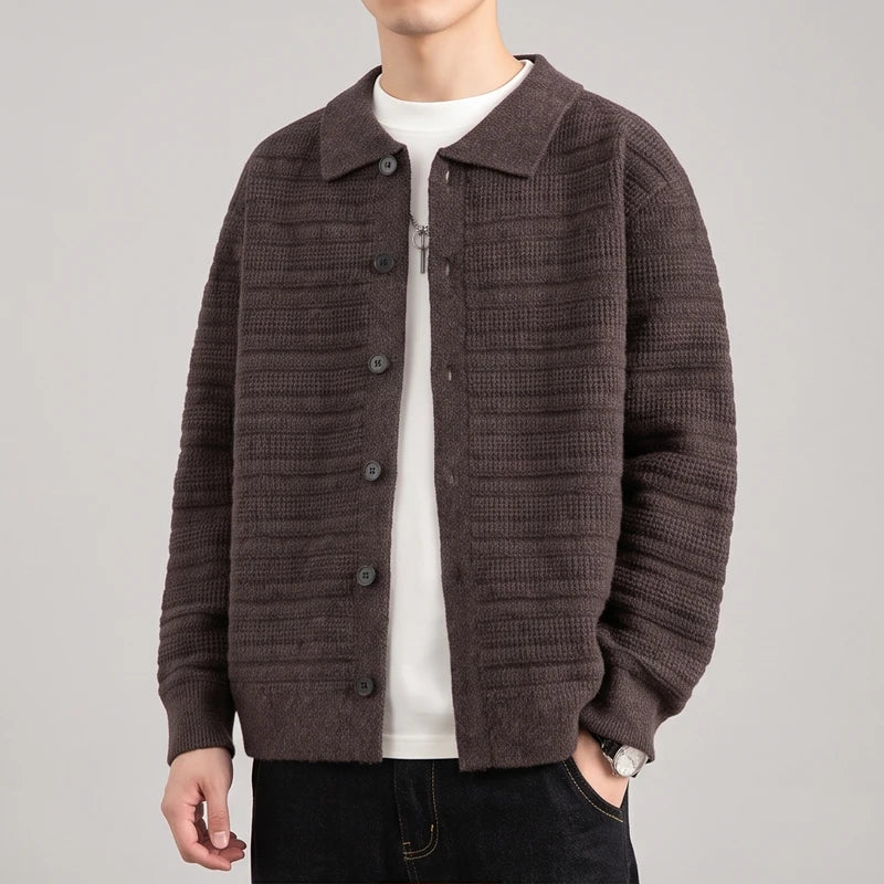 Man wearing a brown textured knit cardigan with a collar, black buttons, and a white t-shirt underneath, standing casually.