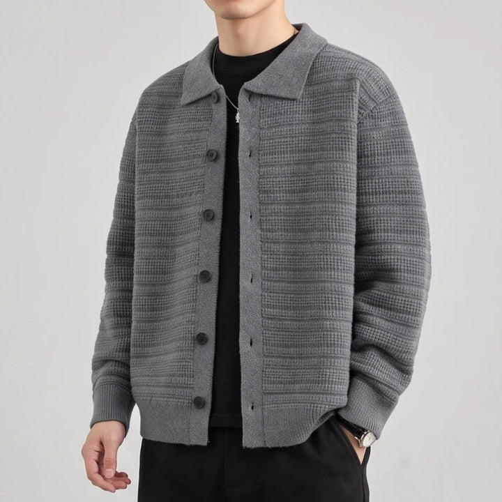 Man wearing an open gray knit cardigan with a shirt collar, textured pattern, and dark buttons over a black t-shirt.