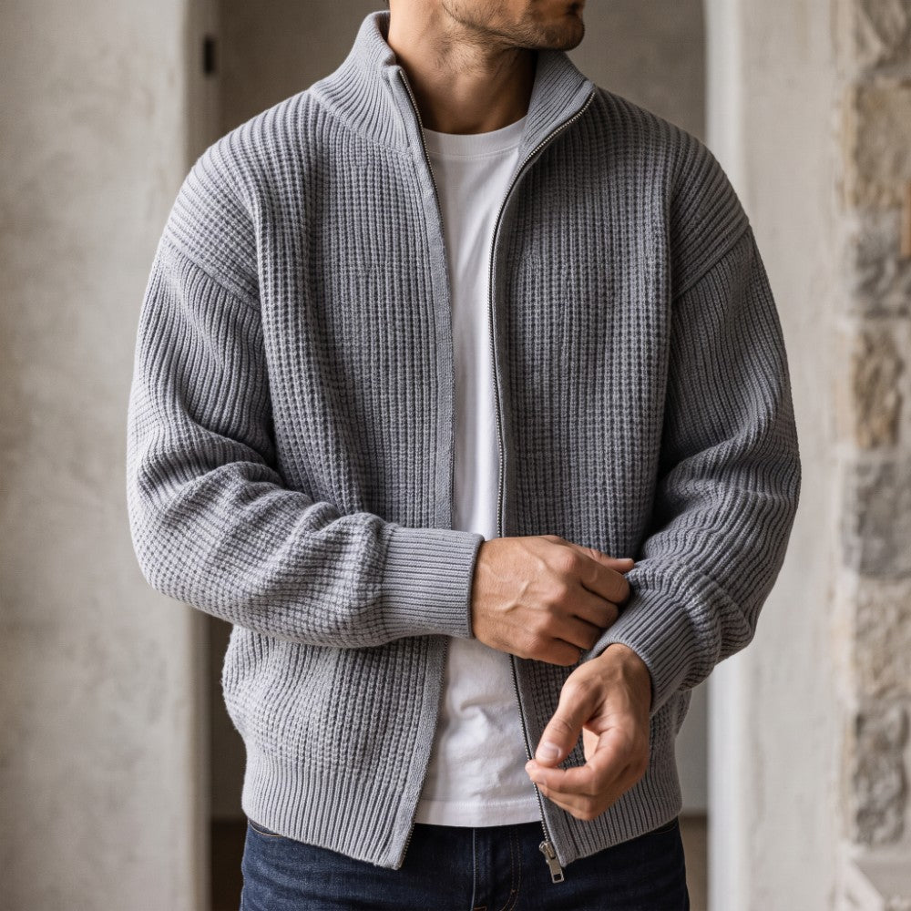 Man wearing a grey waffle knit zip-up cardigan over a white t-shirt and dark jeans.