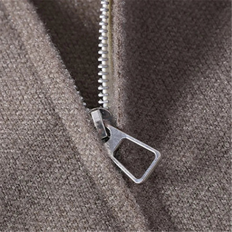 Close-up of a silver zipper on a textured brownish-grey knit sweater, featuring a rectangular zipper pull.