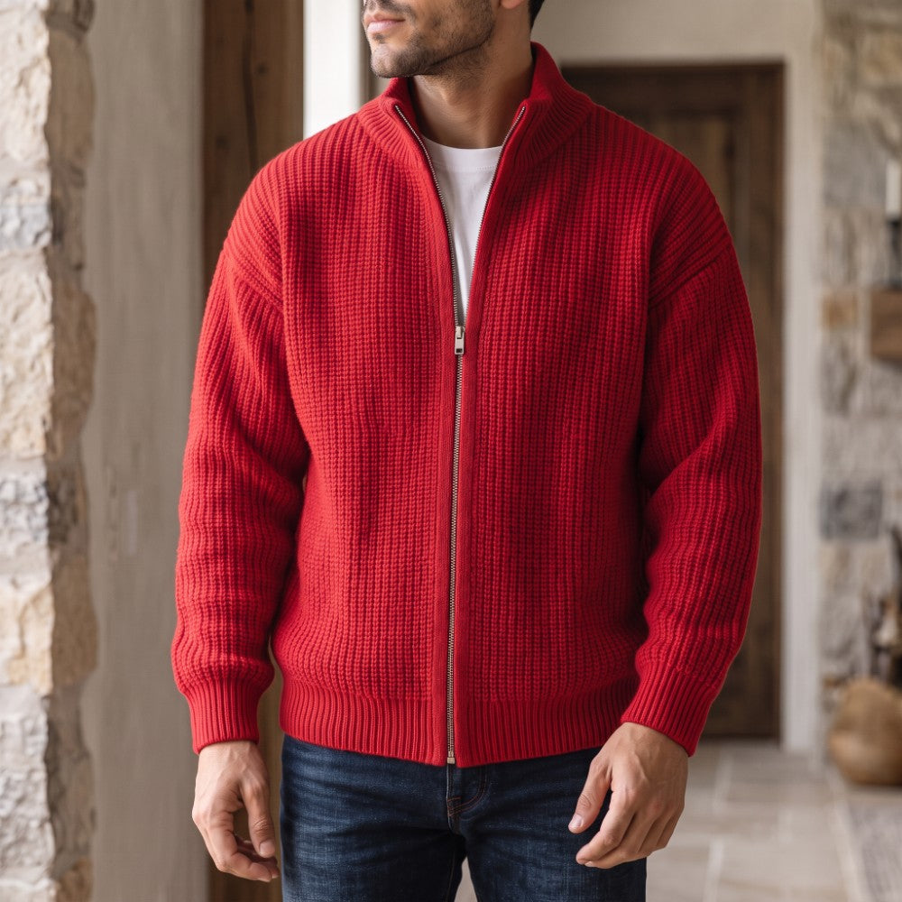 Man wearing a red knit cardigan sweater with a stand collar and silver zipper over a white tee, dark blue jeans.