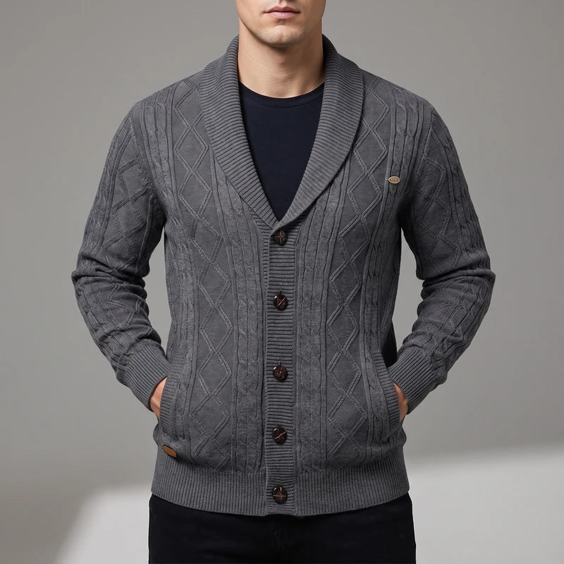 Man wearing a dark gray knitted cardigan with diamond cable pattern, shawl collar, and dark brown buttons.
