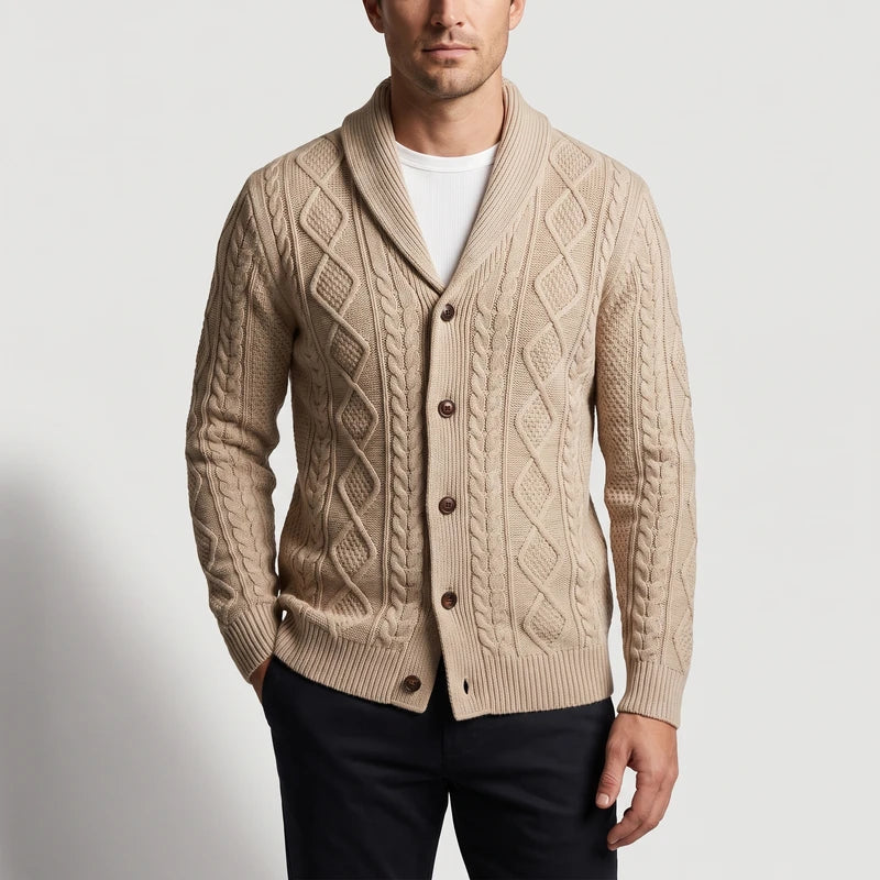 Man wearing a light tan cable knit cardigan with a large shawl collar and brown buttons, over a white t-shirt.