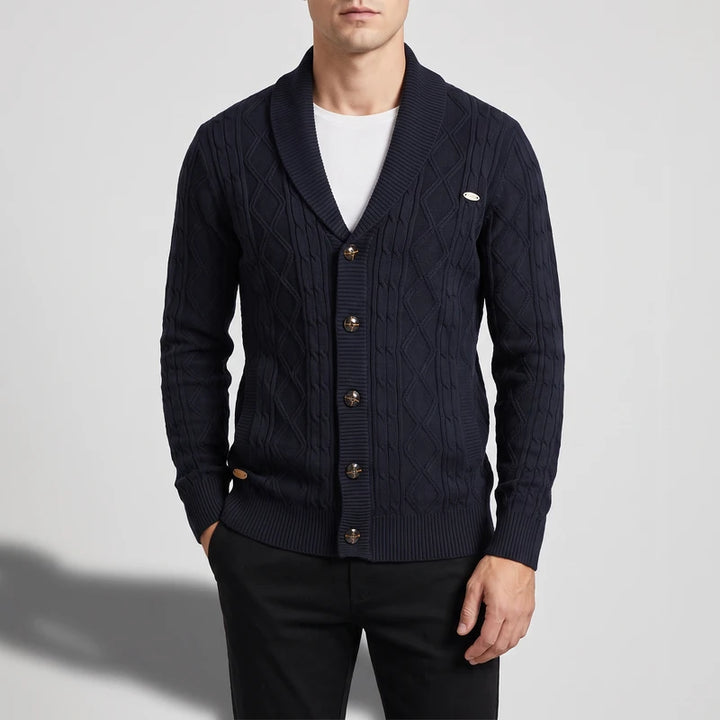 Man wearing a navy blue cable knit shawl collar cardigan with bronze buttons over a white t-shirt.