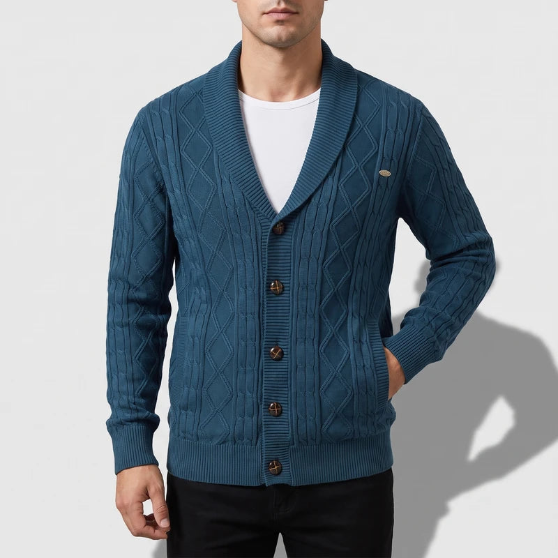Man wearing a teal blue cable knit cardigan with a shawl collar, wooden buttons, and two front pockets.