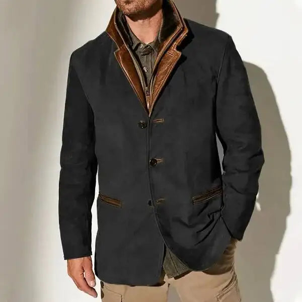 Man wearing a dark gray jacket with brown leather lapels, three buttons, and brown trim over a patterned shirt.