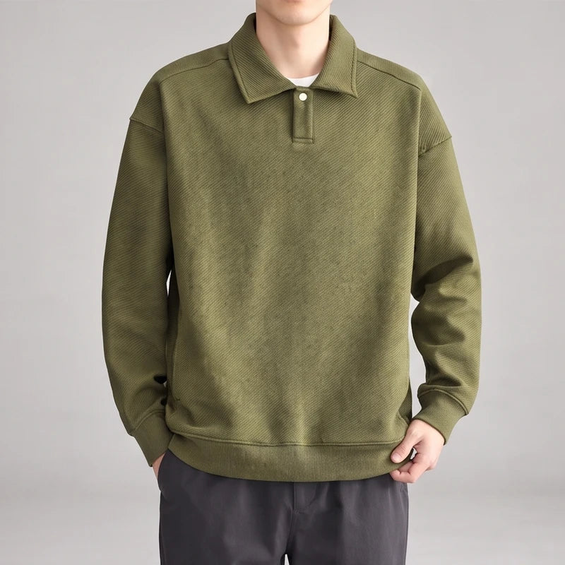 Man wearing a relaxed-fit olive green long-sleeve polo sweatshirt with a diagonal ribbed texture and single button placket.