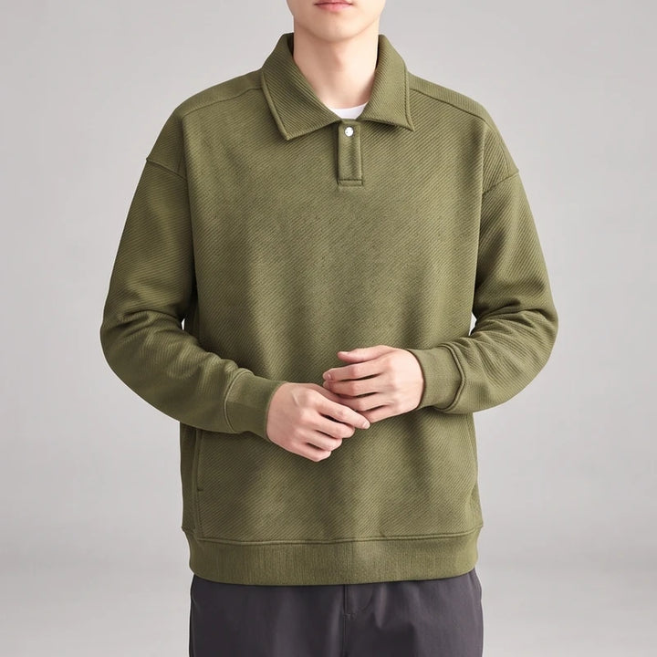 Man wearing a dark olive green long-sleeve polo shirt with a subtle diagonal textured pattern and single white button.