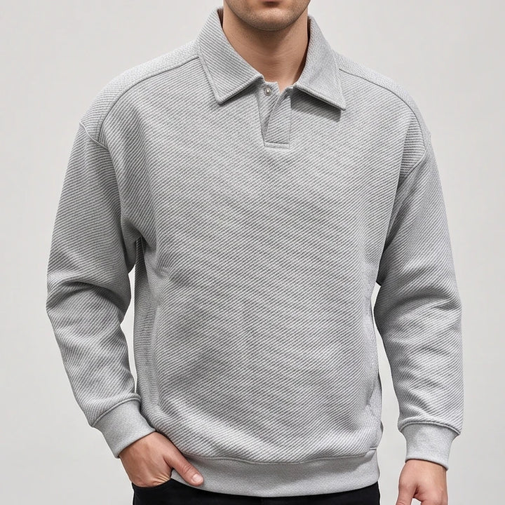 Man wearing a light grey long-sleeve polo sweatshirt with a textured diagonal stripe pattern and two snap buttons.