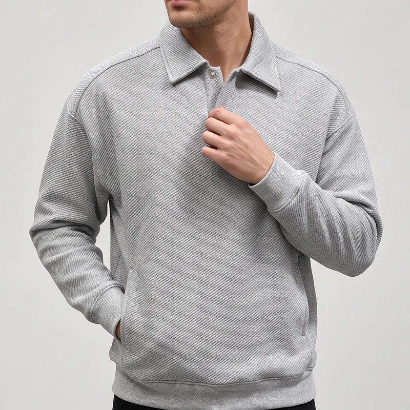 Man wearing a light gray long-sleeve polo sweatshirt with a subtle diagonal textured pattern and rib-knit cuffs.