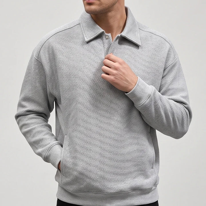 Man wearing a light gray long-sleeve polo sweatshirt with a subtle diagonal textured pattern and rib-knit cuffs.