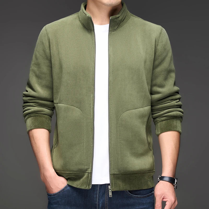 Man wearing a dark green textured zip-up jacket with a stand-up collar, ribbed cuffs, and side pockets.