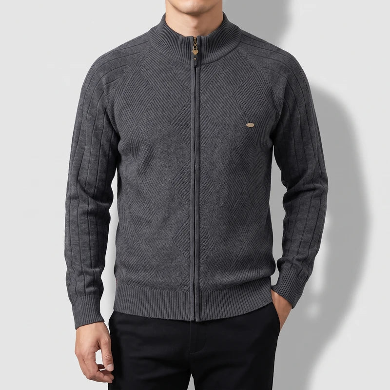 Man wearing a dark gray knit zip-up sweater with a high collar and a subtle diamond pattern on the front.