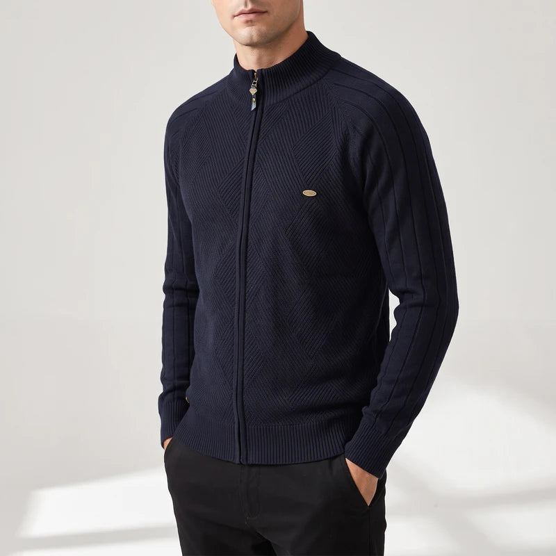 Man wearing a dark navy zip-up knit sweater with a stand collar, unique chest texture, and gold zipper.